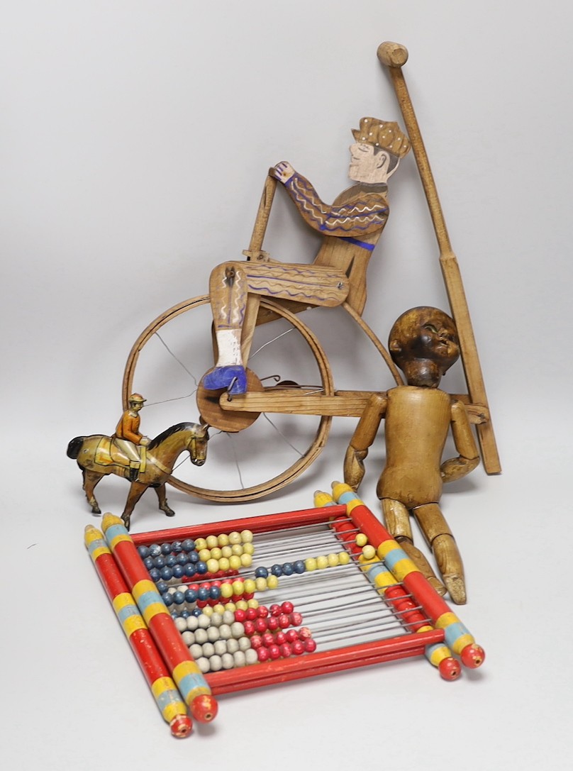 A Victorian carved pine jointed peg doll, jointed wood uni-cyclist toy, two abacuses and an early 20th century German tin plate and clockwork jockey on racehorse
